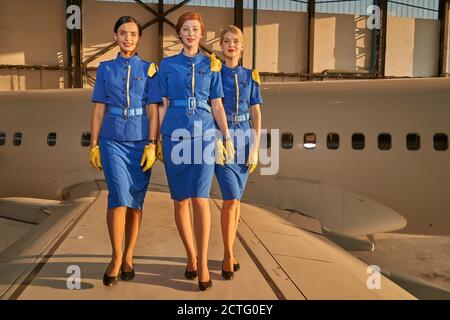 Drei hübsche Flugbegleiter lächeln und gehen Stockfoto