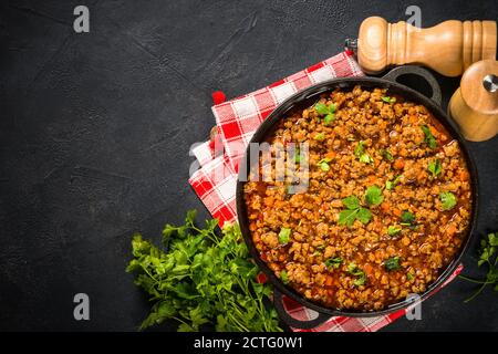 Bolognese steht in Eisenplatte am schwarzen Tisch. Stockfoto
