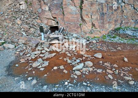 Mann am Stolleneingang zur unterirdischen Goldmine, rostfarbenes Wasser kommt aus dem Tunnel, Straße zum Clear Lake, San Juan Mountains, Colorado, USA Stockfoto