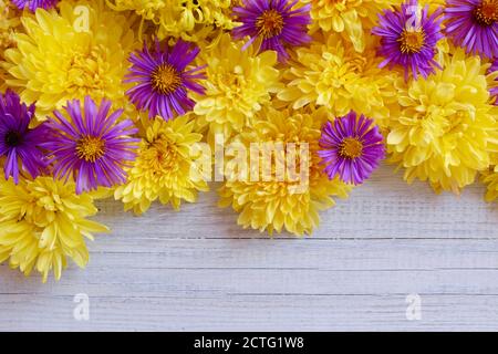 Blumenrahmen von gelben Chrysanthemen auf einem weißen Holzhintergrund. Platz und Draufsicht kopieren. Stockfoto