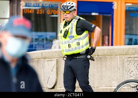 Ein Polizist ist auf der High Street aus dem Stadtzentrum von Paisley, die einschließlich anderer Städte in Renfrewshire, hat zusätzliche Lockdown Maßnahmen gegen Mitternacht letzte Nacht hinzugefügt entdeckt. Aufgrund eines Spikes in Covid-19 Fällen. Kredit: Euan Cherry Stockfoto