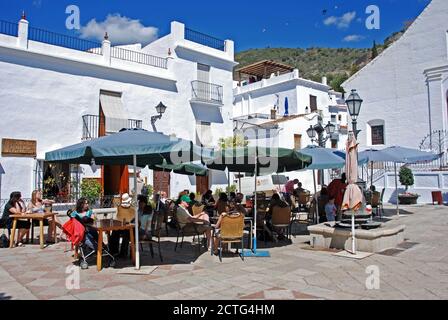 Touristen entspannen an einem Straßencafé auf dem Kirchplatz (Plaza de la Iglesia), Frigiliana, Spanien. Stockfoto