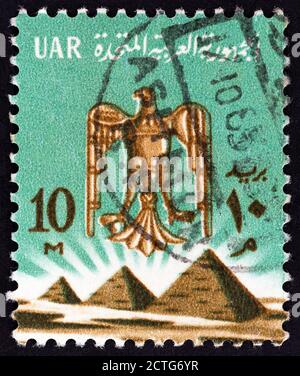 ÄGYPTEN - UM 1964: Eine in Ägypten gedruckte Briefmarke zeigt das Adler-Emblem und die drei Pyramiden bei Gizeh, um 1964. Stockfoto