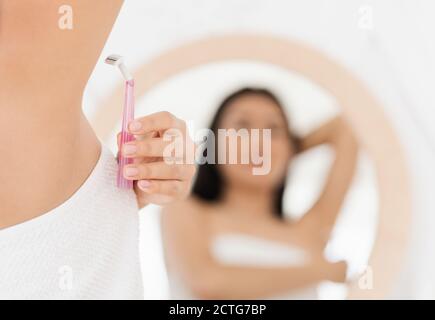 Unkenntlich Frau rasieren Achsel mit Rasiermesser im Badezimmer Stockfoto