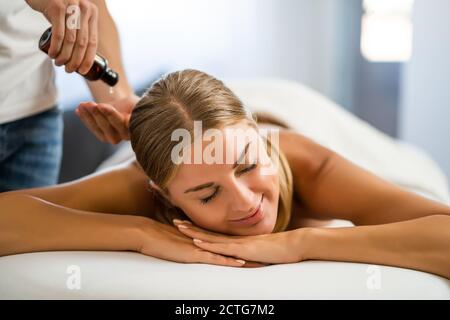 Professionelle Masseur tun therapeutische Massage. Frau genießt Massage in ihrem Haus. Junge Frau bekommen entspannende Körpermassage. Stockfoto