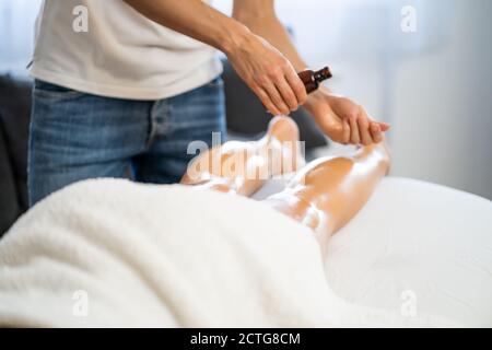 Professionelle Masseur tun therapeutische Massage. Frau genießt Massage in ihrem Haus. Junge Frau bekommen entspannende Körpermassage. Stockfoto