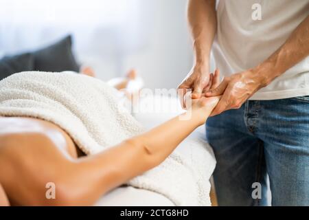 Professionelle Masseur tun therapeutische Massage. Frau genießt Massage in ihrem Haus. Junge Frau bekommen entspannende Körpermassage. Stockfoto