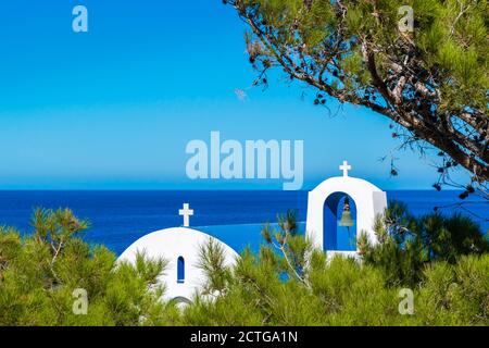 Kirche Kuppel und Glockenturm versteckt in Kiefer Baum, mit Blick auf Ägäis in Karpathos Insel, Dodekanes, Griechenland Stockfoto