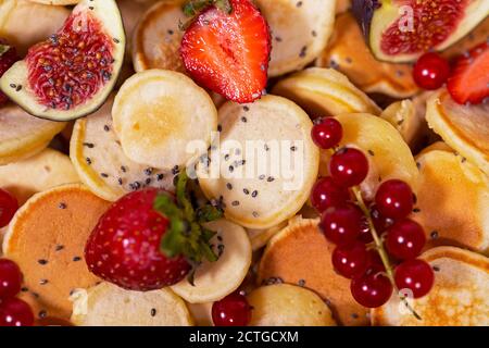 Kleine Pfannkuchen mit Erdbeere, Johannisbeere und Feigenschleichen. Blick von oben auf das üppige Frühstück. Stockfoto