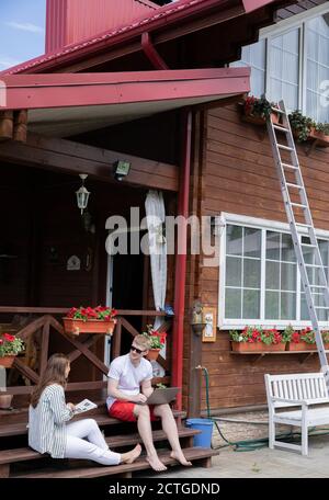 Junge, moderne Paare, die sich am Sommerwochenende im Freien ausruhen und aus der Ferne arbeiten Stockfoto