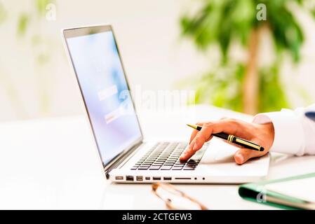 Nahaufnahme der Hand eines Geschäftsmannes beim Tippen auf der Tastatur des Laptops und beim Ablesen von E-Mails. Stockfoto