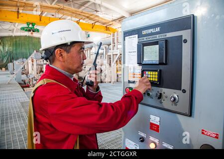 Aktobregion/Kasachstan - Mai 04 2012: Ölraffinerie-Anlage CNPC company. Bedienfeld der Pumpstation und Techniker mit Funkgerät. Caterpillar Compa Stockfoto