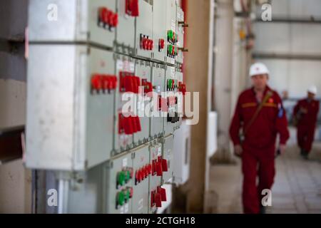 Schalttafel und Fernbedienung (Konsole). Raffineriearbeiter in rot arbeiten Verschleiß von Öl-und Gasverarbeitungsanlage. Unscharf im Hintergrund. Stockfoto
