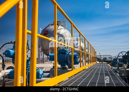 Zhanazhol, Kasachstan:Kugelgasspeicher zur Verflüssigung von Erdöl (Erdgas), Flüssiggas, LNG.Gelbe Balustrade im Fokus, Tank verschwommen. Raffineriewerk. Stockfoto