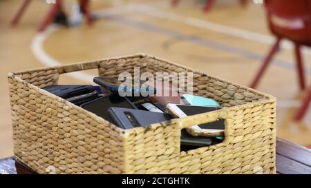 Handy kostenlos Klassenzimmer und Schulen. Ein Speichercontainer, der mit mehreren Telefonen von Studenten oder Benutzern gefüllt ist. Rohrkorb mit Mobile gefüllt Stockfoto