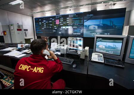 Ölraffinerie-Werk. Betriebsleitstelle und Bediener in rot Arbeitskleidung sieht auf Monitoren aus. CNPC-Unternehmen. Stockfoto