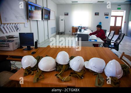 Kontrollraum der Ölraffinerie und Gasverarbeitungsanlage. Bediener des Computersystems und Monitore verschwommen. Weiße Hüte im Vordergrund im Fokus. Stockfoto