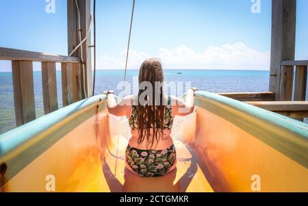 SAN PEDRO, BELIZE - Apr 16, 2019: Eine weibliche Touristin fährt eine Rutsche in die Karibik im El Diablo Aqua Park im Caribbean Villas Resort auf Amber Stockfoto