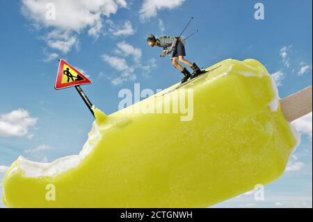 Mini-Bergskifahrer, die schnell auf dem Eishügel mit Gefahrenschild und Graben auf dem sonnigen blauen Himmel fahren, konzeptuelle Szene des Wintersports Stockfoto