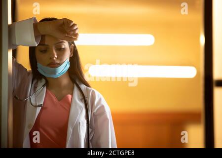 Doktor, der sich an die Tür lehnte und danach eine Pause einnahm Ein hektischer Arbeitstag Stockfoto