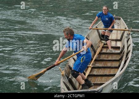 Männer und Frauen in einem Schweizer Fischer traditionellen Holzboot auf Sportveranstaltung. Sie stehen und bewegen das Schiff mit Rudern auf der Limmat. Stockfoto