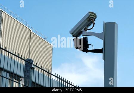 CCTV-Überwachungskamera auf einem Pfosten, Fabrikhof der privaten Firma aus Sicherheitsgründen mit blauem Himmel als Hintergrund zu beobachten. Stockfoto