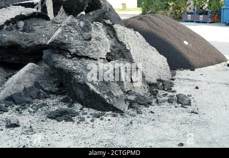 Gebrochene große Teile der beschädigten Asphaltschicht und zerkleinerte Steine aus alten Straße bilden Schutt als Prozess der Erneuerung der Einfahrt. Stockfoto