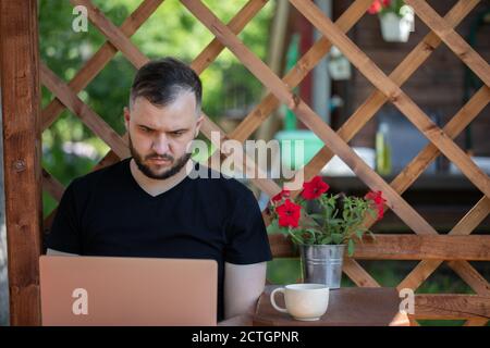 Entfernung Arbeitskonzept junger Mann arbeitet mit Laptop auf Holz Pergola Stockfoto