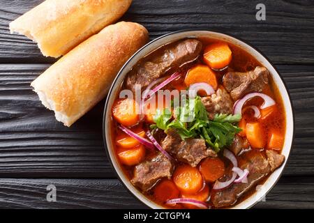 Bo Kho Rindfleisch-Ragout in würziger Sauce mit Karotten serviert mit vietnamesischem Brot close-up in einer Schüssel auf dem Tisch. Horizontale Draufsicht von oben Stockfoto