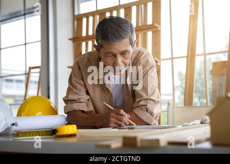 Asian alter Mann arbeitet in Schreinerei Werkstatt. Konzept Senioren Hobby nach dem Ruhestand. Stockfoto