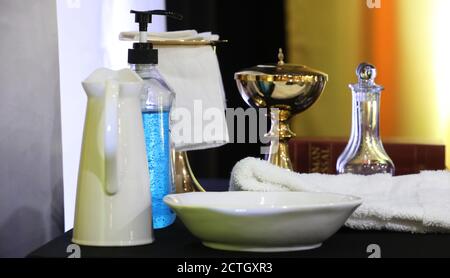 Blauer Hand-Santizer im Fokus. Covid sichere heilige Kommunion. Covid-19 katholische Messe in der Kirche serviert. Desinfektionsmittel mit Weihwasser Wein und Gastgeber Kelch Stockfoto