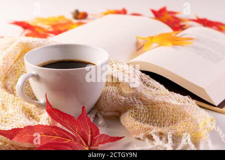 Herbstblätter, Tasse Kaffee, Buch lesen warmen Schal und geöffnetes Buch auf dem Tisch. Selektiver Fokus. Stockfoto