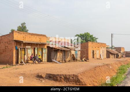 Kapapi / Uganda - Februar 26 2020: Erwachsene afrikanische Männer sitzen untätig vor einem Gebäude und entspannen sich. Stockfoto