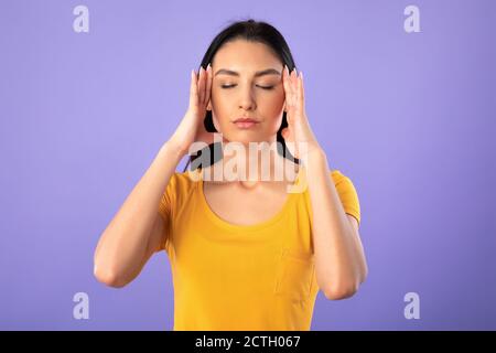 Porträt einer jungen Frau, die die Finger auf den Schläfen hält Stockfoto