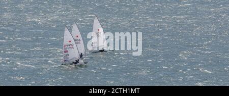 Portland Harbour, Vereinigtes Königreich - 3. Juli 2020: High Angle Panorama Aufnahme von drei Laser Class Racing Schlauchboote, die dicht beieinander segeln Stockfoto