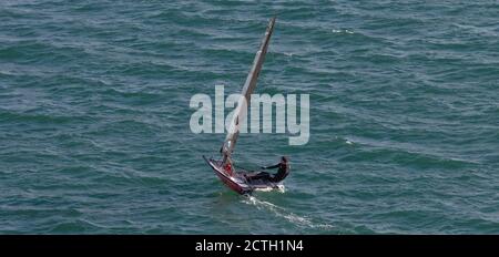 Portland Harbour, Vereinigtes Königreich - 2. Juli 2020: High Angle Panoramaaufnahme eines einzelnen Rennbootes im Hafen von Portland. Mann trägt schwarz schwimmen Stockfoto