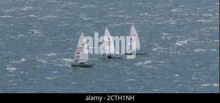 Portland Harbour, Vereinigtes Königreich - 3. Juli 2020: High Angle Panorama Aufnahme von drei Laser Class Racing Schlauchboote, die dicht beieinander segeln Stockfoto