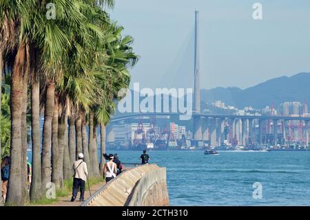 Uferpromenade in Sheung Wan, Hong Kong mit Victoria Harbour und Stonecutters Bridge im Hintergrund Stockfoto