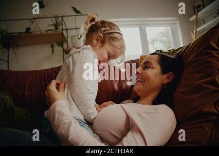 Mutter und Tochter spielen zusammen auf der Couch zu Hause - Mutter und Tochter lachen zusammen Stockfoto
