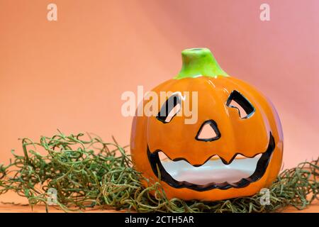 Halloween Kürbis Tee Licht Dekoration auf einem Bett aus Gras mit orangefarbenen Hintergrund und Kopierer Raum. Stockfoto