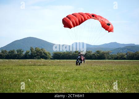 Der einzelne Fallschirmspringer, der aus dem Flugzeug gesprungen ist, benutzt einen Fallschirm, um zu landen. Einfaches Konzept mit Copy Space Photograph. Stockfoto