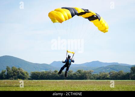 Der einzelne Fallschirmspringer, der aus dem Flugzeug gesprungen ist, benutzt einen Fallschirm, um zu landen. Einfaches Konzept mit Copy Space Photograph. Stockfoto