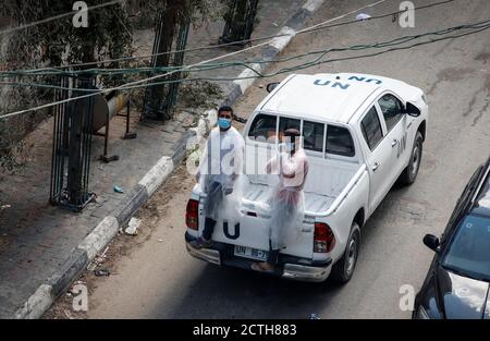 Gaza, Palästina. September 2020. Palästinensische Arbeiter, die maskiert sind, werden hinter einem Pickup-Lastwagen der Vereinten Nationen gesehen, während sie zum Lebensmittelverteilunglager Jabalia fahren.palästinensische Arbeiter und das Hilfswerk der Vereinten Nationen für palästinensische Flüchtlinge (UNRWA) liefern Nahrungsmittelhilfe-Rationen in die Häuser des Lagers Jabalia im nördlichen Gazastreifen, Anstatt sie in einem UN-Zentrum zu verteilen, wie es normalerweise aufgrund der COVID-19-Pandemie geschieht. Kredit: SOPA Images Limited/Alamy Live Nachrichten Stockfoto