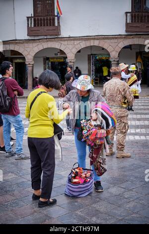 Ein Straßenverkäufer, der Souvenirs Erinnerungsstücke an einen Touristen während des Sonnenfestes Inti Raymi'rata während der Wintersonnenwende in Cusco, Peru verkauft Stockfoto