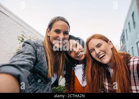 Schöne junge Frau im Gespräch Selfie mit Freunden stehen zusammen. Gruppe von Frauen in der Stadt machen ein Selbstporträt. Stockfoto