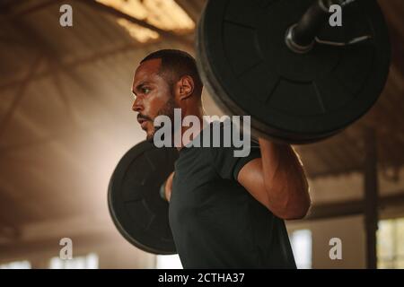 Mann trainiert mit Langhantel. Männliche Bodybuilder tun Gewichtheben Training im Cross-Training Turnhalle. Stockfoto