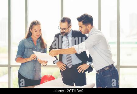 Team von multiethnischen Architekten arbeiten an Bauplänen im Besprechungsraum. Ingenieure diskutieren über Projekt im Büro. Reifer Geschäftsmann und Frau Stockfoto
