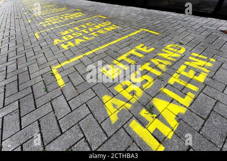 Dortmund, 23. September 2020: BITTE ABSTAND halten! Markierungen auf dem Boden vor dem bvb09 Fanshop im Signal Iduna Park (Westfalenstadion) in Dortmund --- Dortmund, 23.09.2020: > BITTE STEHEN HALTEN!< Markierungen auf dem Boden vor dem Fanshop des bvb09 am Signal Iduna Park (Westfalenstadion) in Dortmund Stockfoto