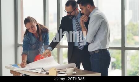 Team von multiethnischen Architekten arbeiten an Bauplänen im Besprechungsraum. Ingenieure diskutieren über Projekt im Büro. Reifer Geschäftsmann und Frau Stockfoto