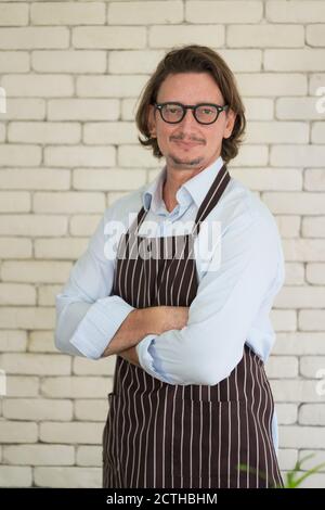 Glücklicher Gärtner Porträt, schöner junger Mann auf Wand Backstein Hintergrund Blick auf die Kamera Stockfoto